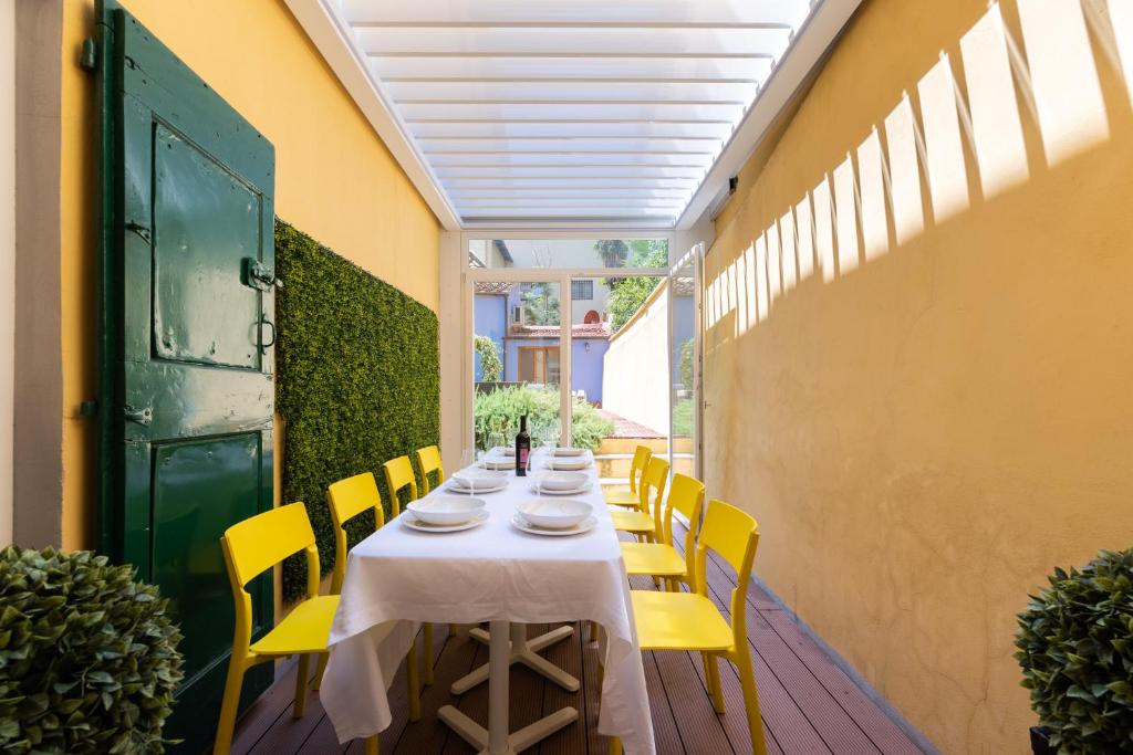een lange tafel met gele stoelen en een groene deur bij SCALA GARDEN Apartment in Florence