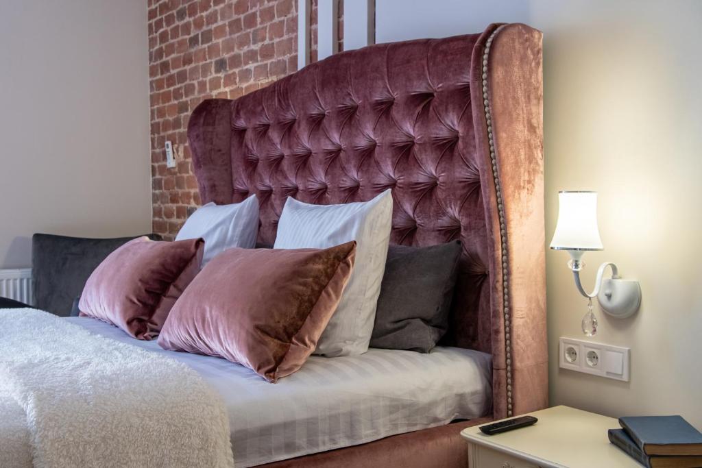 a bed with a large padded headboard with pillows at LVIV -APART центр 2 кім ізольовані і кухня студія in Lviv