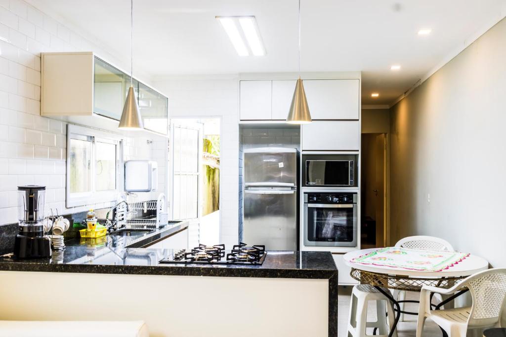 une cuisine avec des appareils électroménagers blancs et une table avec des chaises dans l'établissement Casas aconchegantes, à São Sebastião