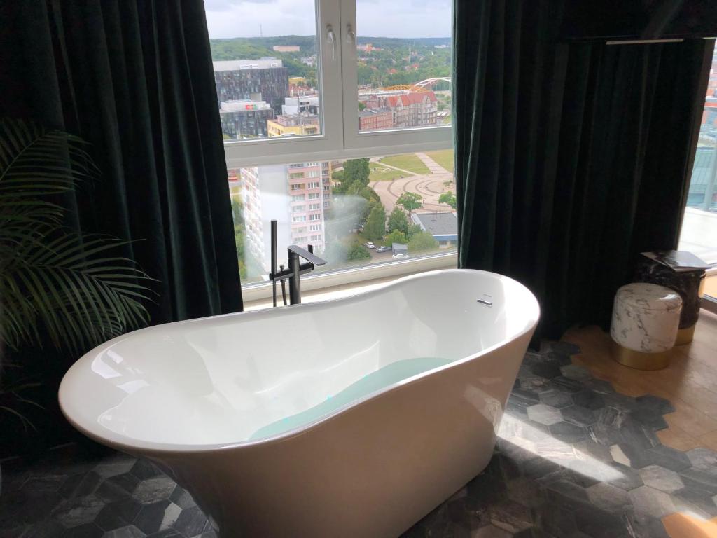 a bath tub in a bathroom with a large window at Jacuzzi Suite in Gdańsk