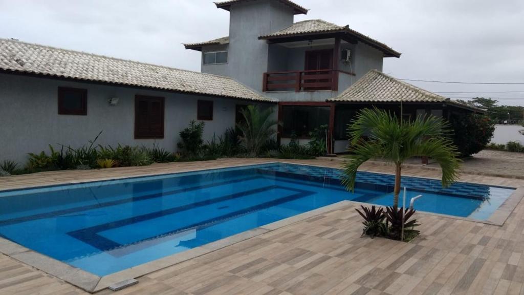 une villa avec une piscine en face d'une maison dans l'établissement Casa Paradiso Temporada em Búzios, à Búzios