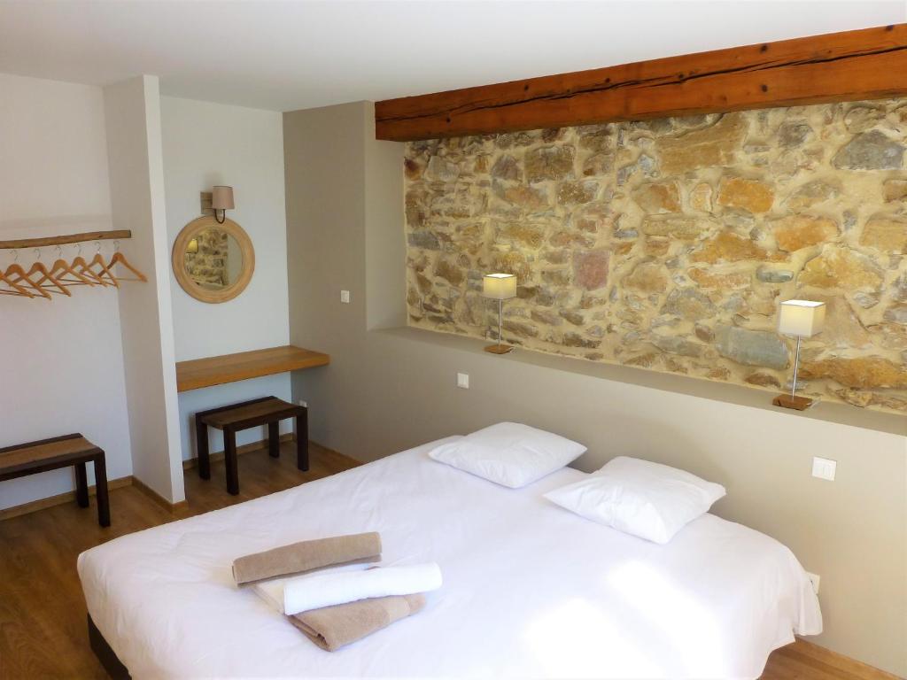 a bedroom with a white bed and a stone wall at L&#39;Accent d&#39;ici in Le Somail