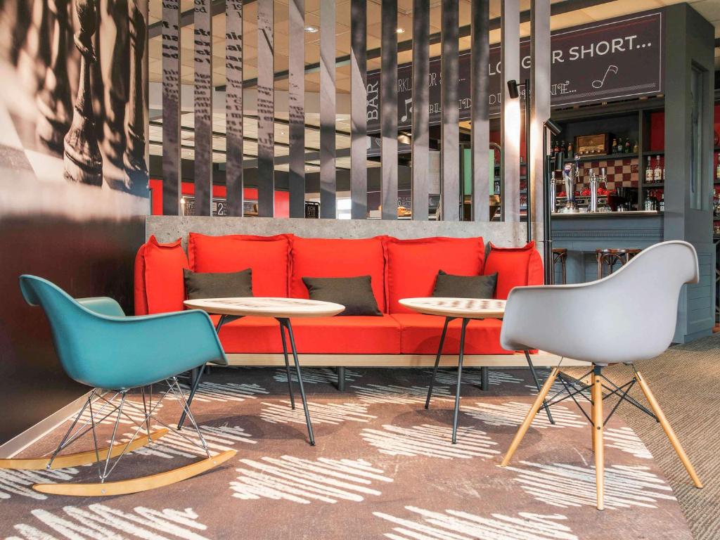 a red couch with two tables and two chairs at ibis Falaise Coeur de Normandie in Falaise