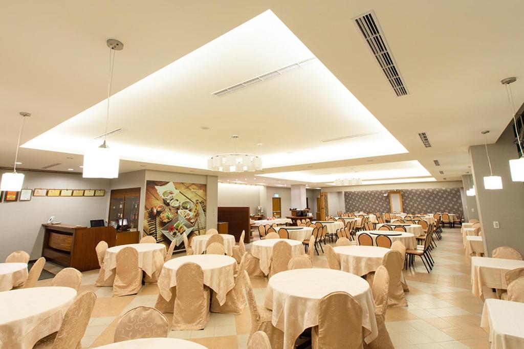 a dining room with white tables and chairs at King&#39;s Resort &amp; Spa in Tai&#39;an