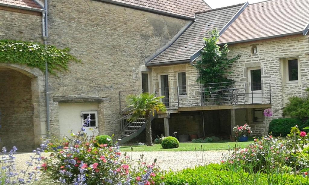 Casa de piedra antigua con balcón y flores en 10 Côté Cour en Chaux