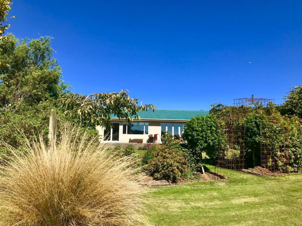 una casa en un patio con césped y árboles en Southland Organic Farmstay, en Invercargill