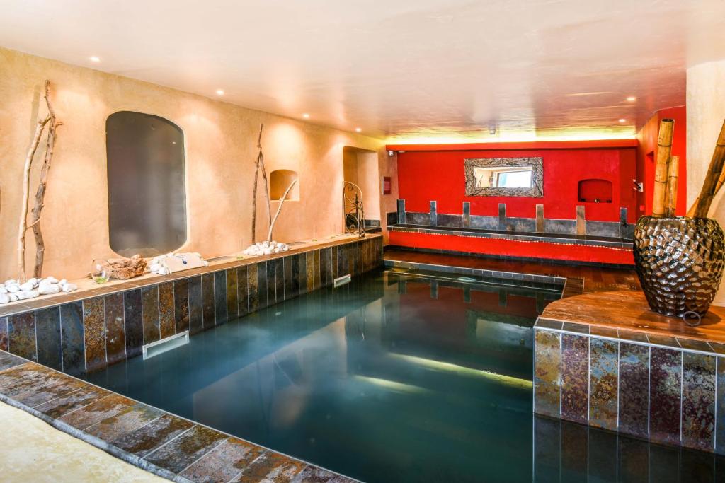 a swimming pool in a hotel room with a red wall at Hôtel Spa Mendi Alde in Ossès