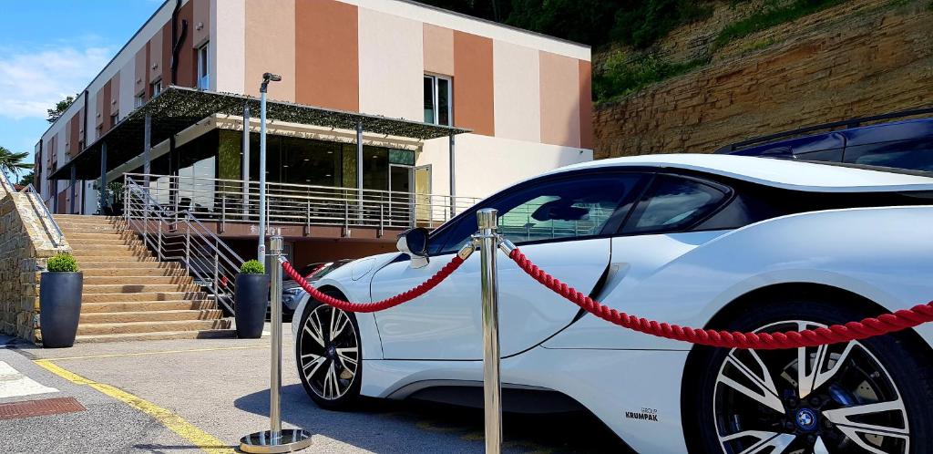 um carro branco estacionado num parque de estacionamento com uma mangueira vermelha em Hotel Lavender - Oleander Resort em Strunjan