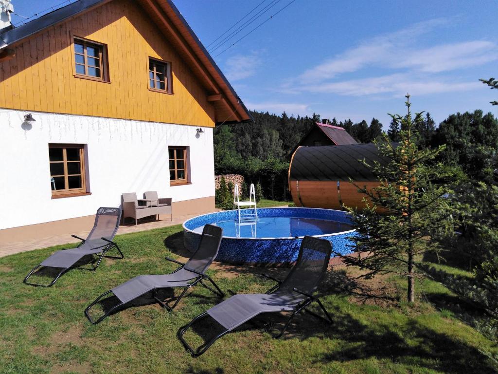 un grupo de sillas y una piscina frente a una casa en Chalupy Vichrovky, en Bělá pod Pradědem