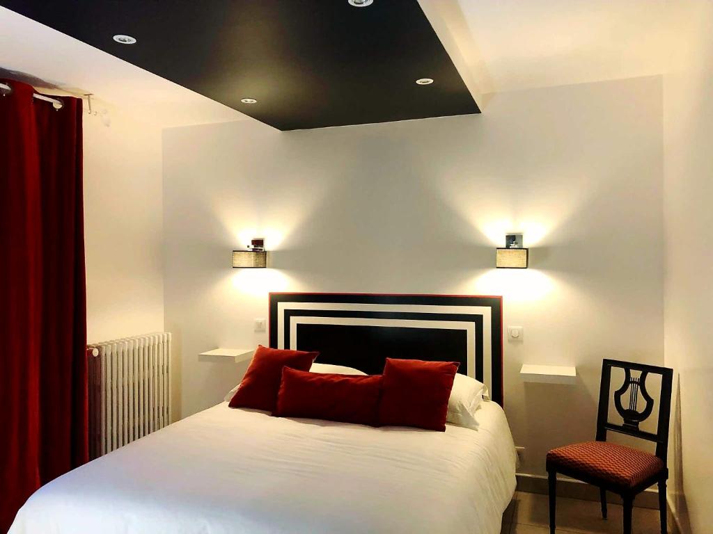 a bedroom with a bed with red pillows and a chair at coté remparts in Provins