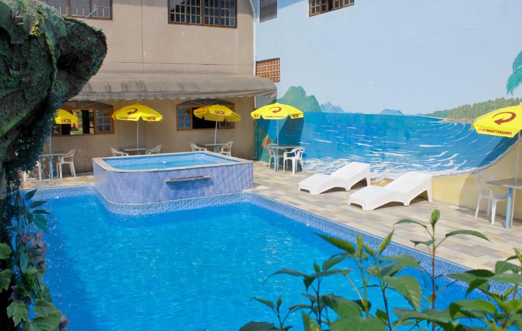 einen Pool mit Stühlen und Sonnenschirmen neben einem Gebäude in der Unterkunft Hotel Pousada Portal da Palmeira in Ubatuba