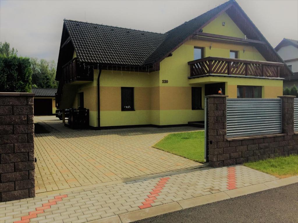 żółty dom z płotem przed nim w obiekcie Apartmány u Slavky w Beszeniowej