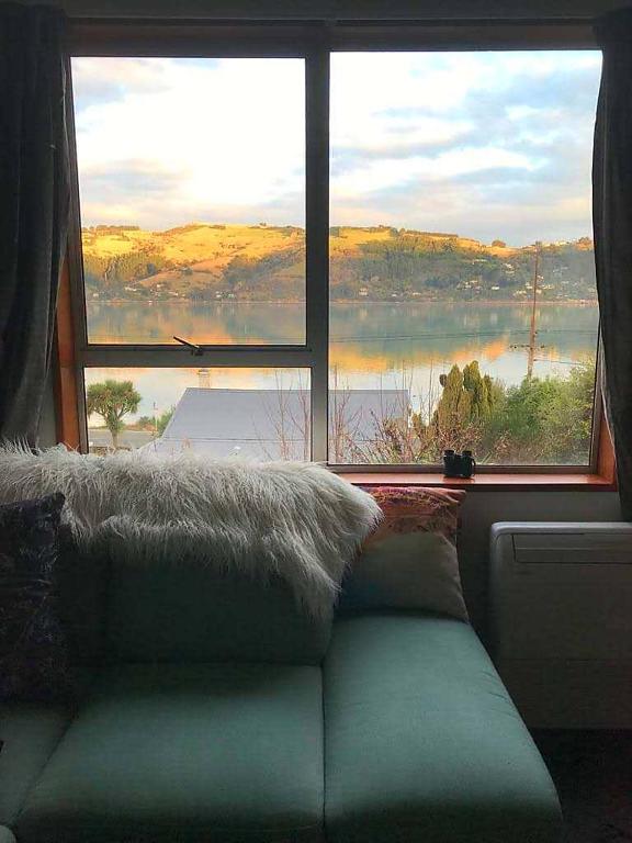 a couch in front of a window with a view at Harbour Side Views in Dunedin