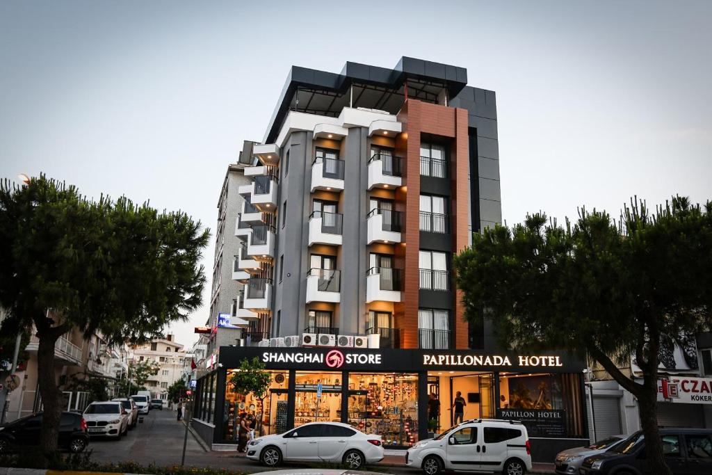 um edifício alto com carros estacionados em frente em PAPİLLONADA HOTEL em Aidim