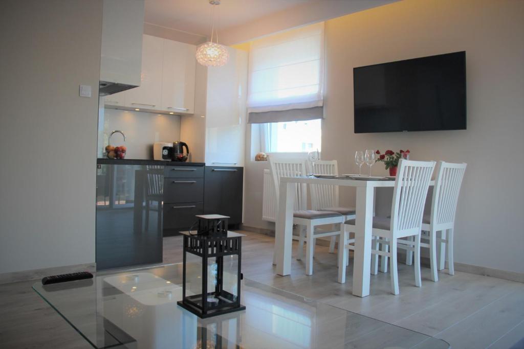 a kitchen and dining room with a white table and chairs at Przy Sosnowym Lesie in Dziwnówek