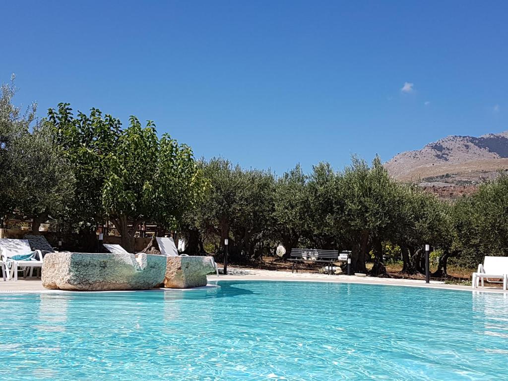 een zwembad met stoelen en bomen op de achtergrond bij Casale la Macina Residence Scopello in Scopello