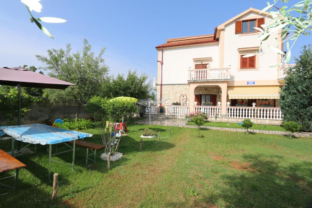 ein Haus mit einem Picknicktisch im Hof in der Unterkunft Apartment Zinka in Šilo