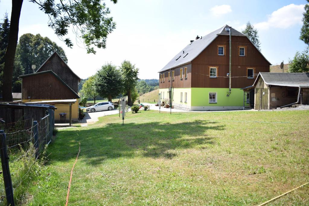 ein großes Grasfeld neben einer großen Scheune in der Unterkunft Ferienwohnung Waldmühle in Saupsdorf