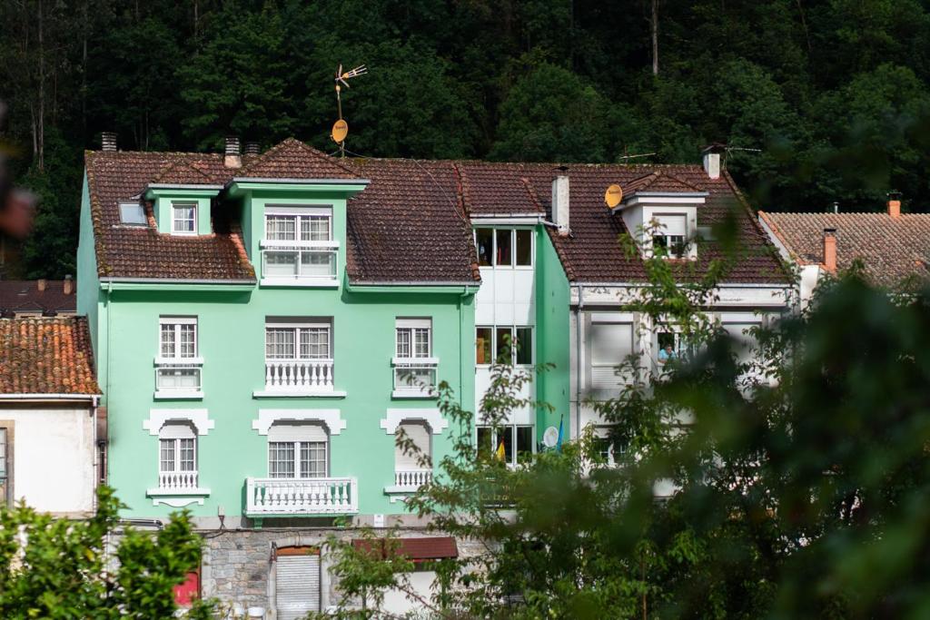un edificio verde con ventanas blancas y techos en Alojamiento Calzada Romana, en Belmonte de Miranda