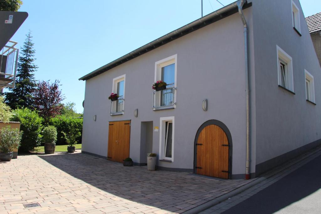 a white building with two windows and a door at Ferienwohnungen Vulkaneifel in Nickenich