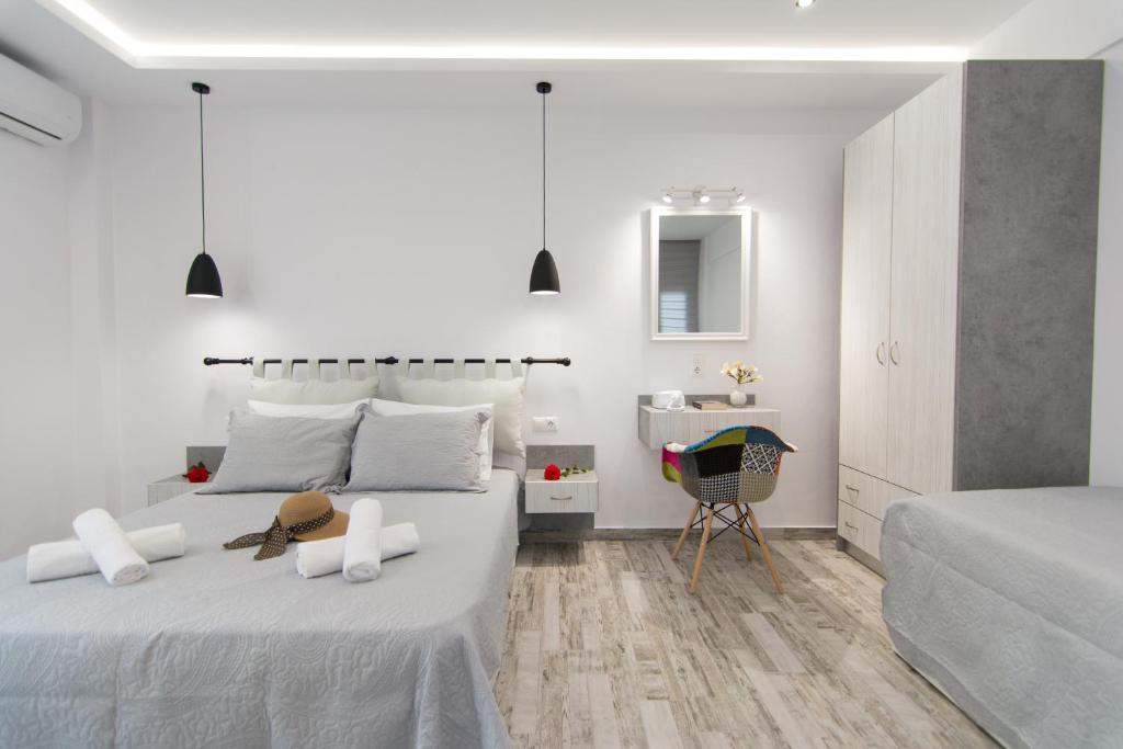 a white bedroom with two beds and a sink at Skalidis Apartments Stalis in Stalida