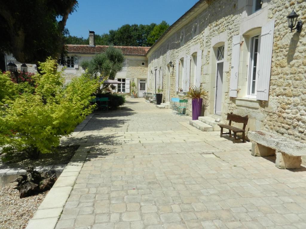 une allée en pierre avec des bancs à côté d'un bâtiment dans l'établissement Jolysable, à Pons
