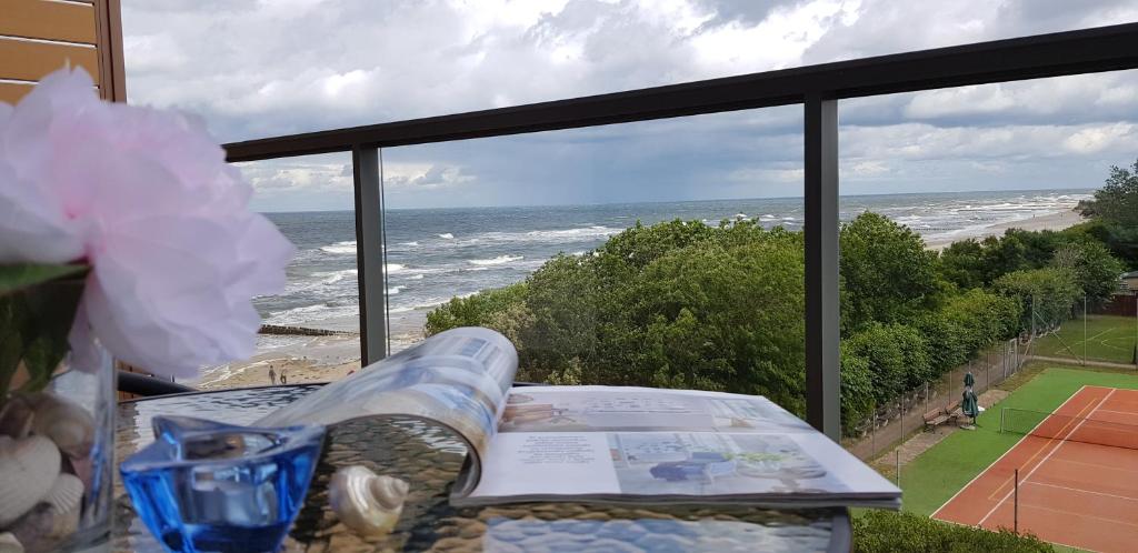 a book on a table with a view of the ocean at Apartament MORSKI WIDOK GARDENIA Dziwnów in Dziwnów