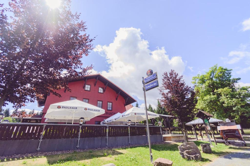 ein Schild im Gras vor einem roten Gebäude in der Unterkunft Hotel und Berggasthof Tanzbuche in Friedrichroda