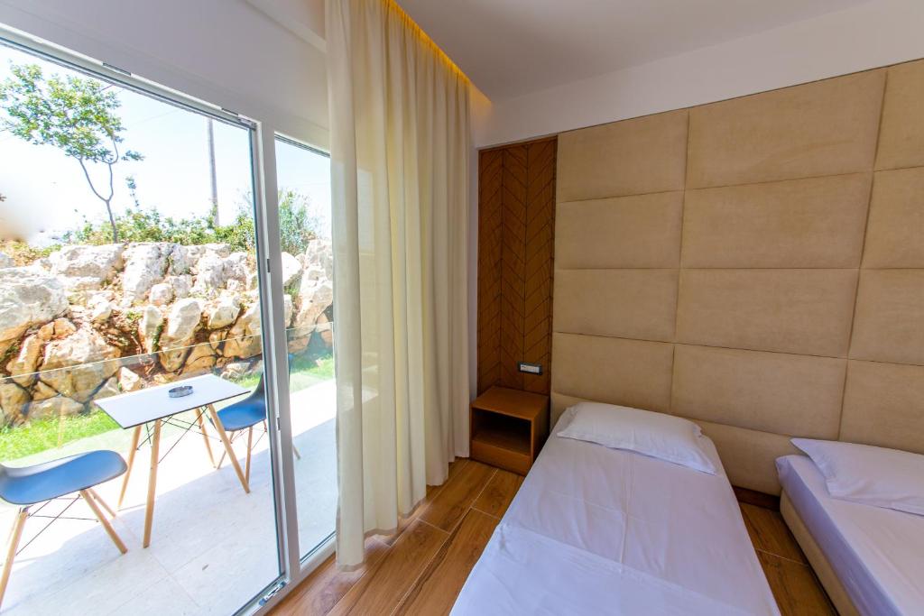 a room with a bed and a table and a window at Inada Hotel Ksamil in Ksamil