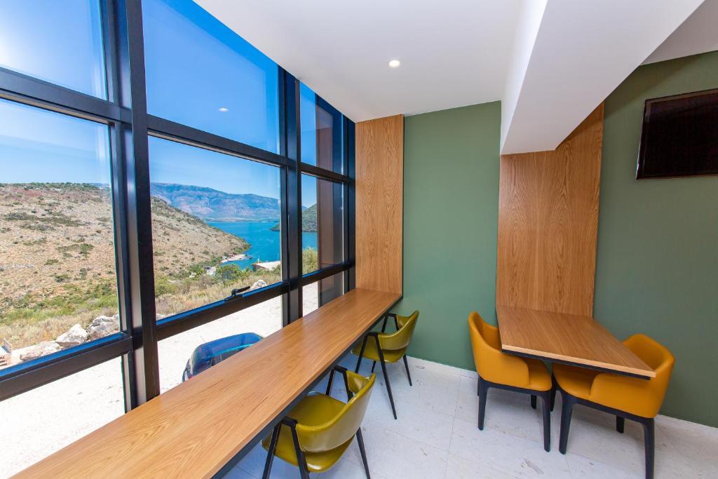 a room with a desk and chairs and a large window at Inada Hotel Ksamil in Ksamil