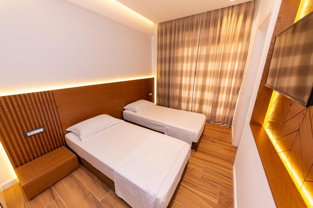 a small room with two beds and a television at Inada Hotel Ksamil in Ksamil