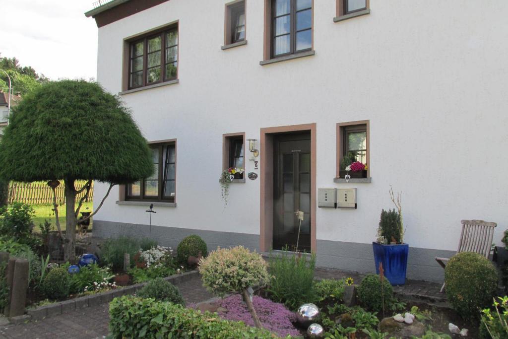una casa blanca con un jardín delante de ella en Gästehaus Fichtenwäldche, en Kelberg