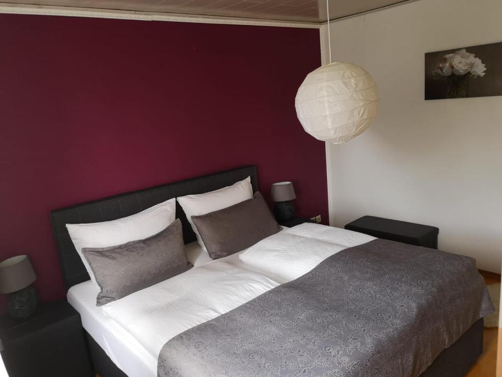 una camera da letto con un grande letto con lenzuola e cuscini bianchi di Ferienwohnung Menden a Menden