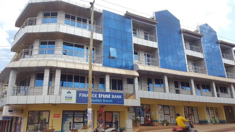 a man riding a motorcycle in front of a building at Hotel Dot Com Entebbe in Entebbe