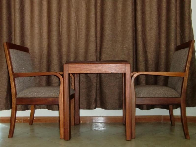 two chairs and a table in front of a curtain at Hotel Dot Com Entebbe in Entebbe