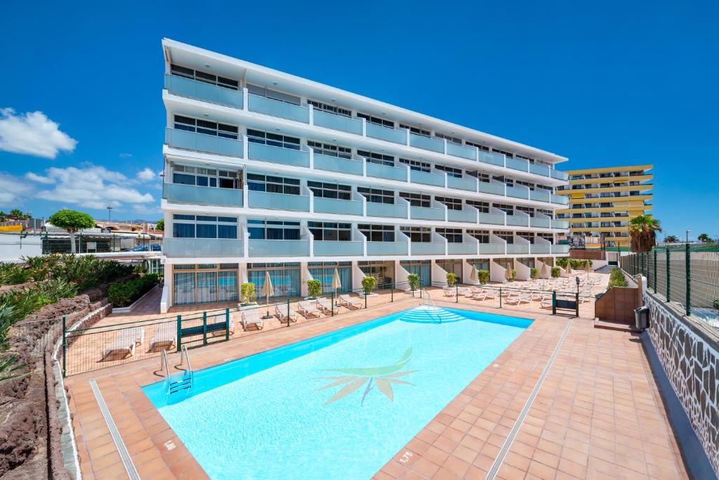 un edificio con piscina di fronte a un edificio di Apartamentos Strelitzias a Playa del Ingles