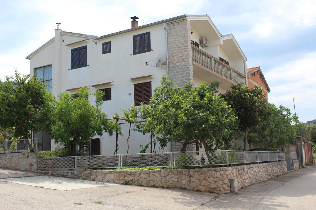 a white house with trees in front of it at Apartman More in Šibenik