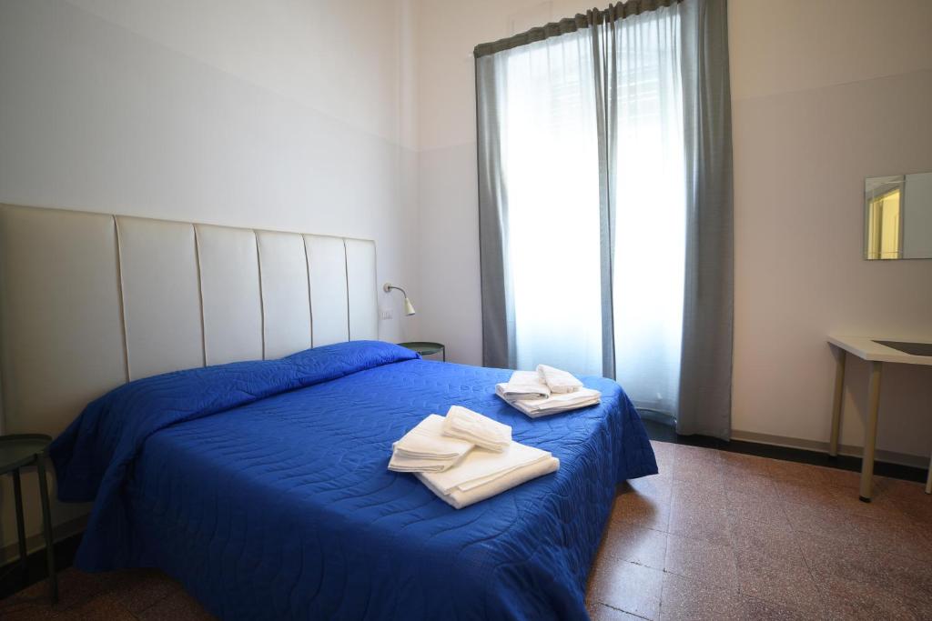 een slaapkamer met een blauw bed en handdoeken bij TIFEO Bed & Breakfast in Catania