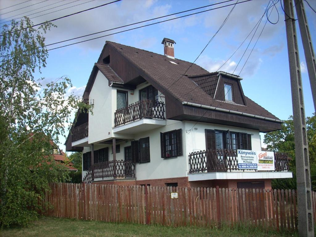 a white house with black windows and a fence at Fanni Vendégház in Miskolctapolca