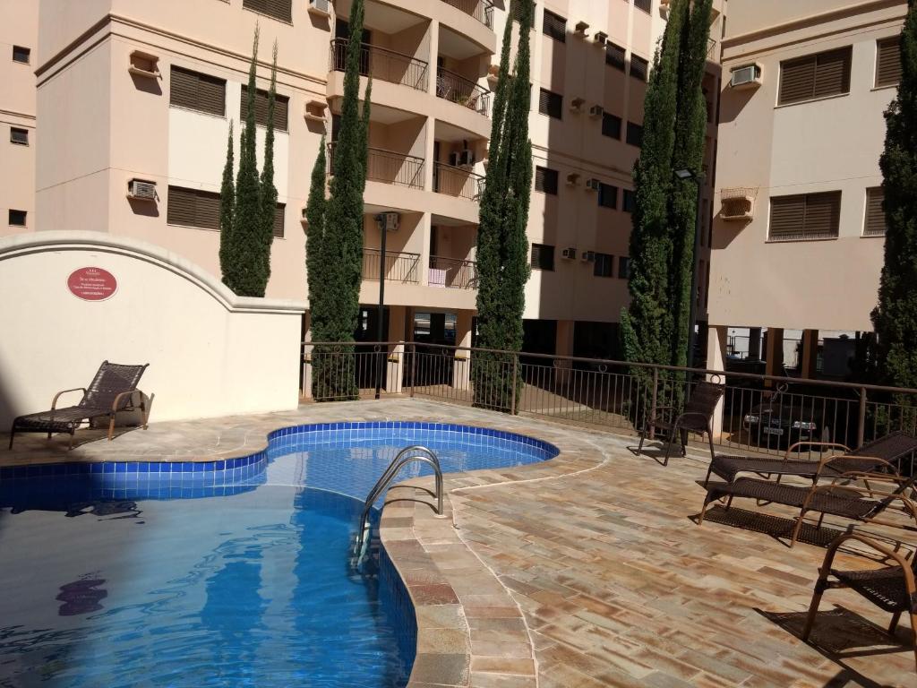 a swimming pool in front of a building with trees at Rê apdetemporadas em Olímpia 63 piscina, WI FI, próximo do Termas O MELHOR P SUA FAMILIA in Olímpia
