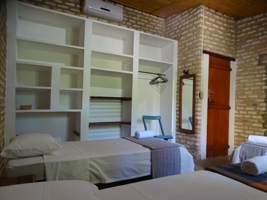 a bedroom with two beds and a brick wall at Pousada Casa do Wolf in São Miguel do Gostoso
