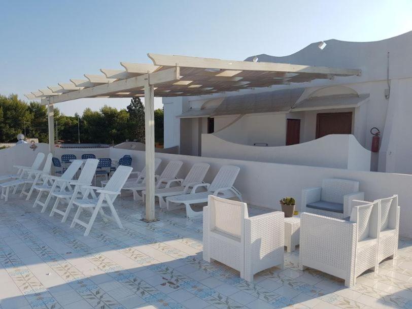 um grupo de cadeiras e mesas brancas num pátio em Villa Giada-8 appartamenti em Leporano