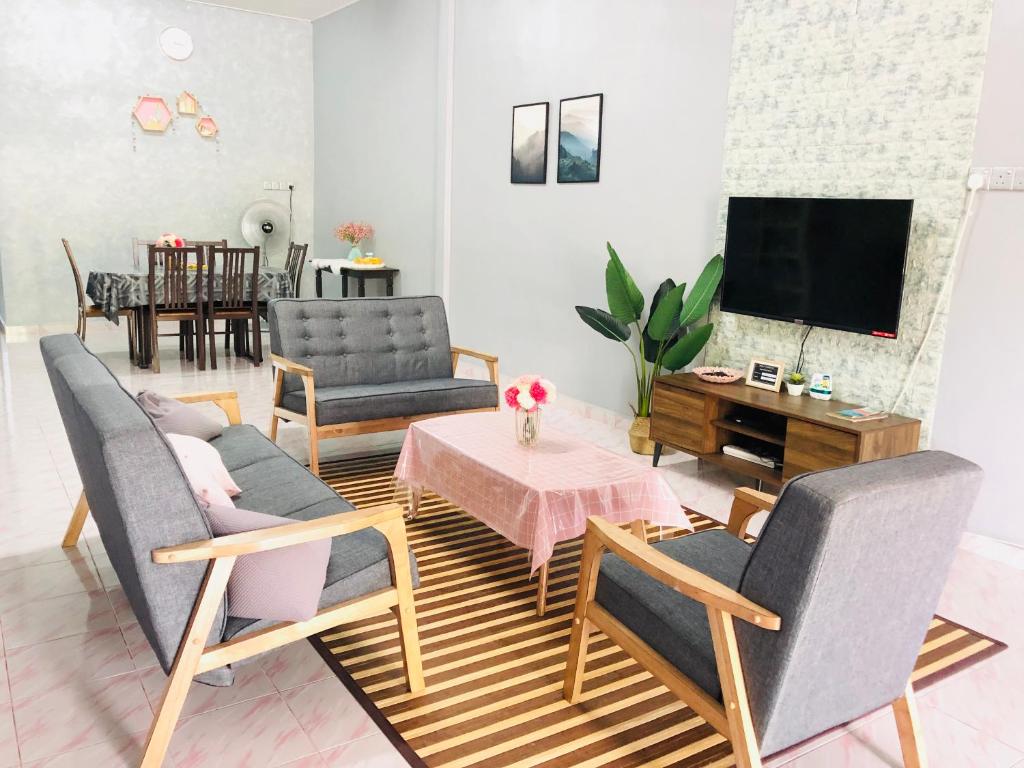 a living room with chairs and a table and a tv at Deena Homestay (Utan Aji) in Kangar