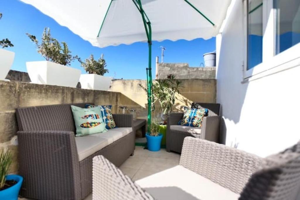 eine Terrasse mit Korbstühlen und einem Sonnenschirm in der Unterkunft MYN Zondadari in Rabat