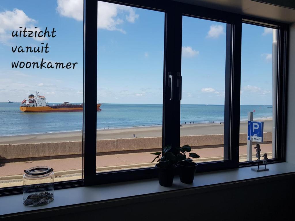 een raam met uitzicht op een strand en een schip bij The Ruyter apartment in Vlissingen