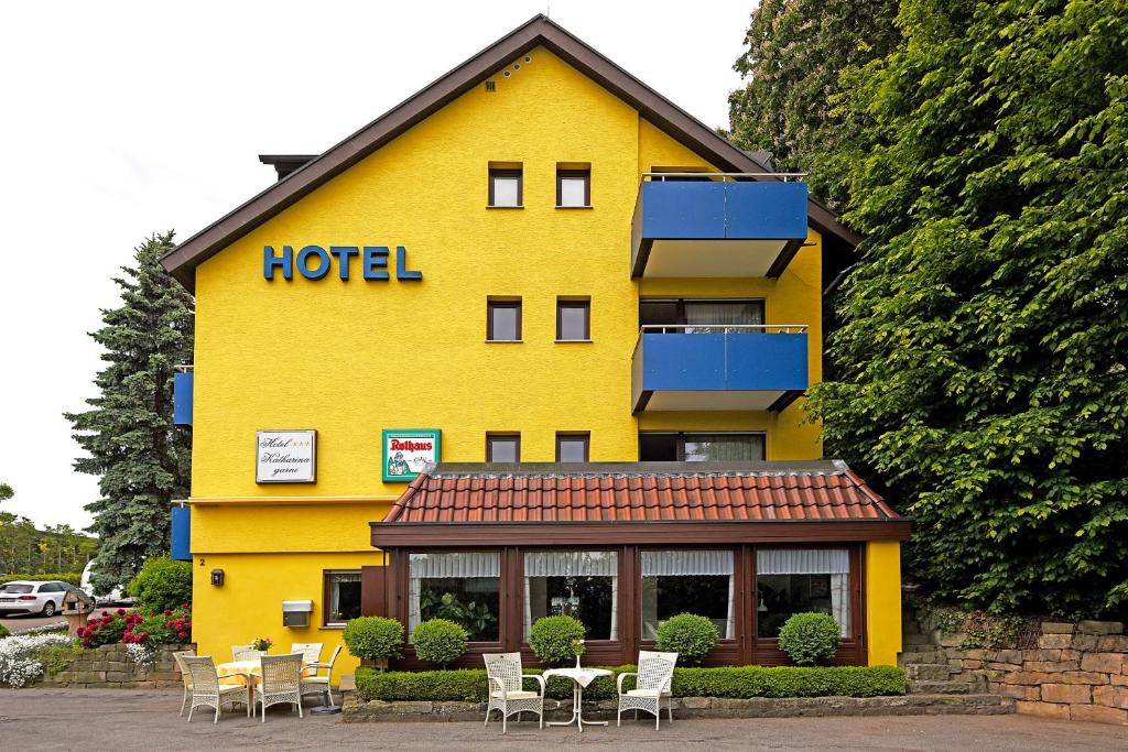 ein gelbes Hotel mit Tischen und Stühlen davor in der Unterkunft Hotel Katharina Garni in Tübingen