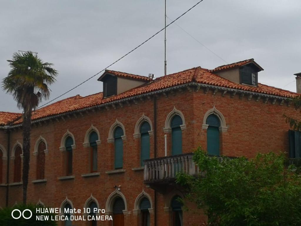 um edifício de tijolos vermelhos com uma palmeira em frente em Cà ARIVANLIAL Venice villa apartament em Lido di Venezia