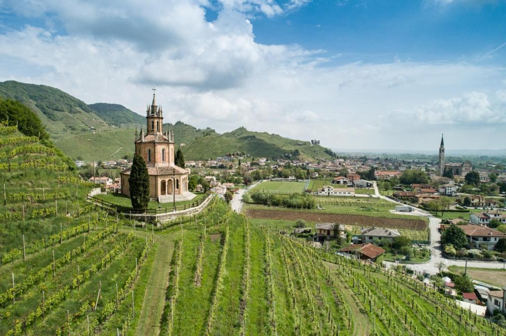 ein Dorf auf einem Hügel mit einer Kirche und Weinbergen in der Unterkunft Oasi di pace nel sito UNESCO del Prosecco DOCG in Farra di Soligo