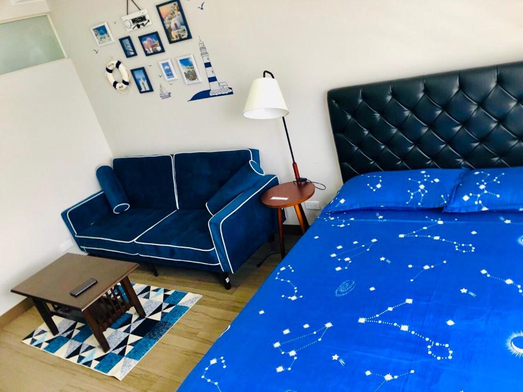 een slaapkamer met een blauw bed en een stoel bij The Sentinel Residences Suite in Manilla