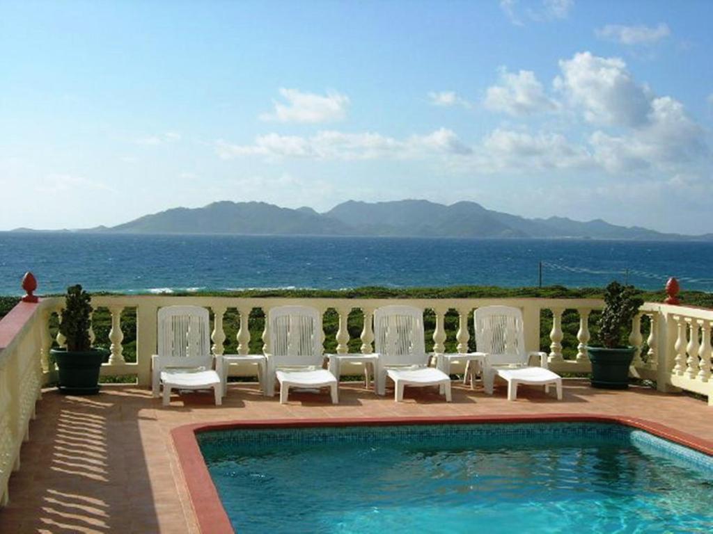 una piscina con sillas y vistas al océano en Ocean Terrace Condominiums en The Valley